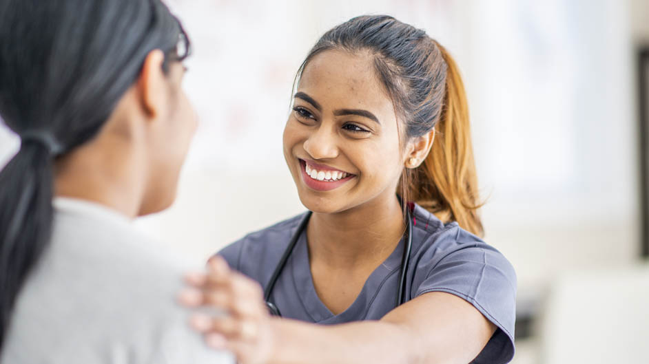 Make A Difference With StarCare A smiling nurse in scrubs places a comforting hand on a patient's shoulder.
